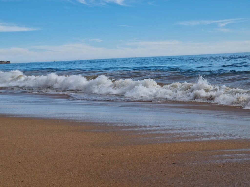 witte schuimrand van de golven van de oceaan met een nat strand
